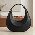 Black Pebbled Textured Half-Moon Hobo Shoulder Bag With Curved Arch Zipper Opening, Single Adjustable Integrated Shoulder Strap And Streamlined Minimalist Silhouette